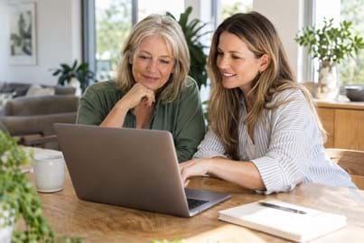 Two women reviewing financial information together on a laptop at home